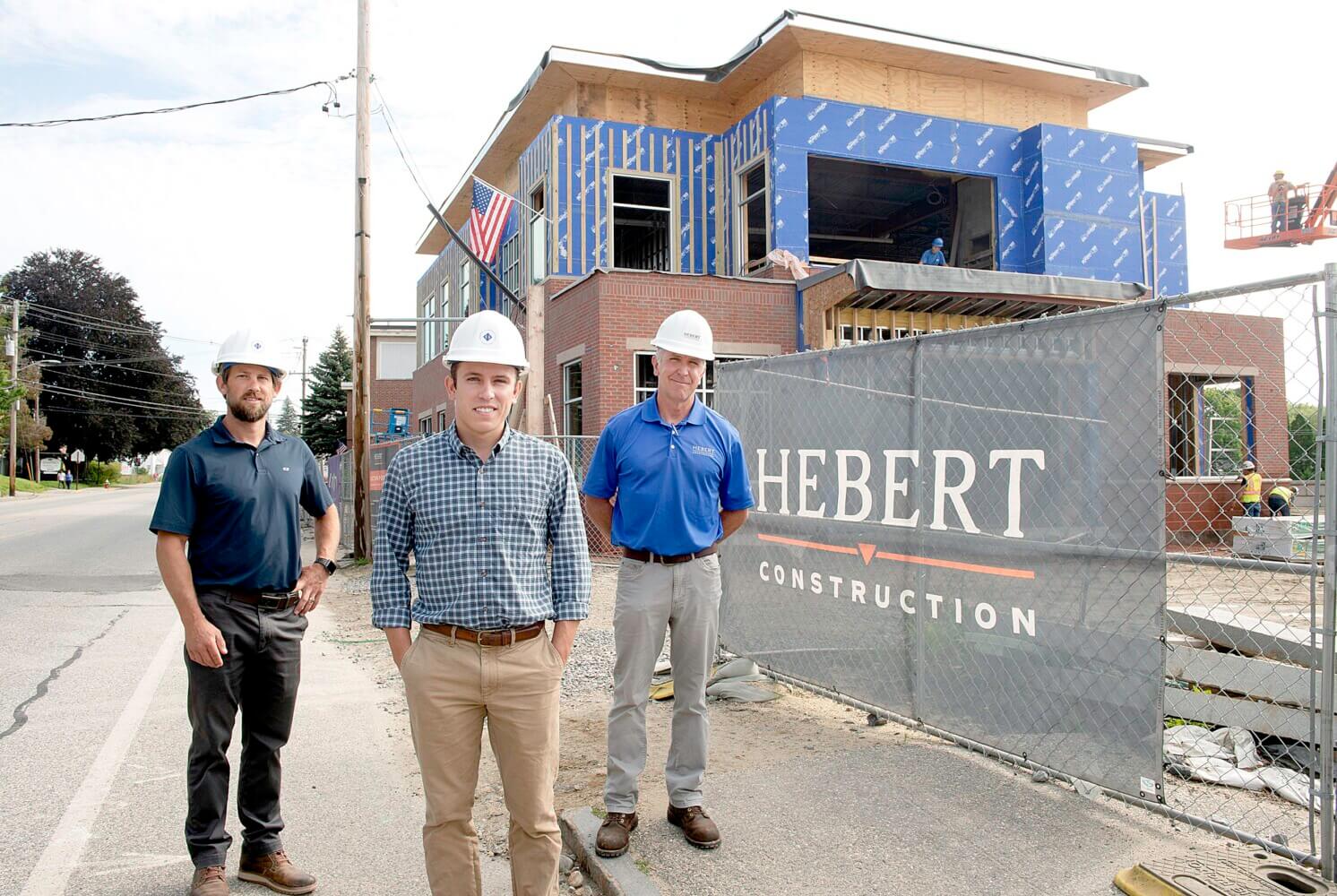 Tim Hebert, Simon Hebert, and Mike Hebert standing in front of a construction project